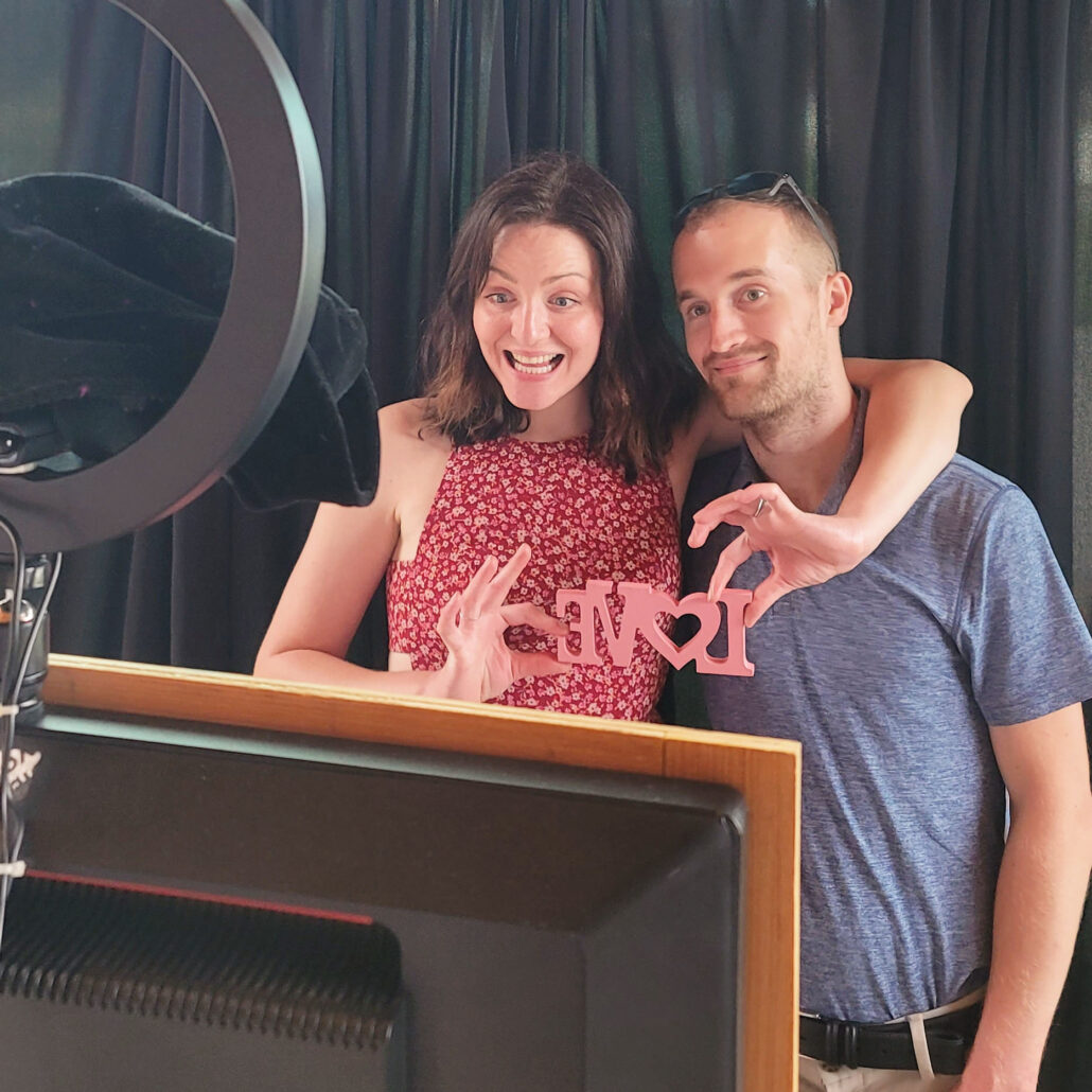 a man and woman standing next to each other in front of a tv